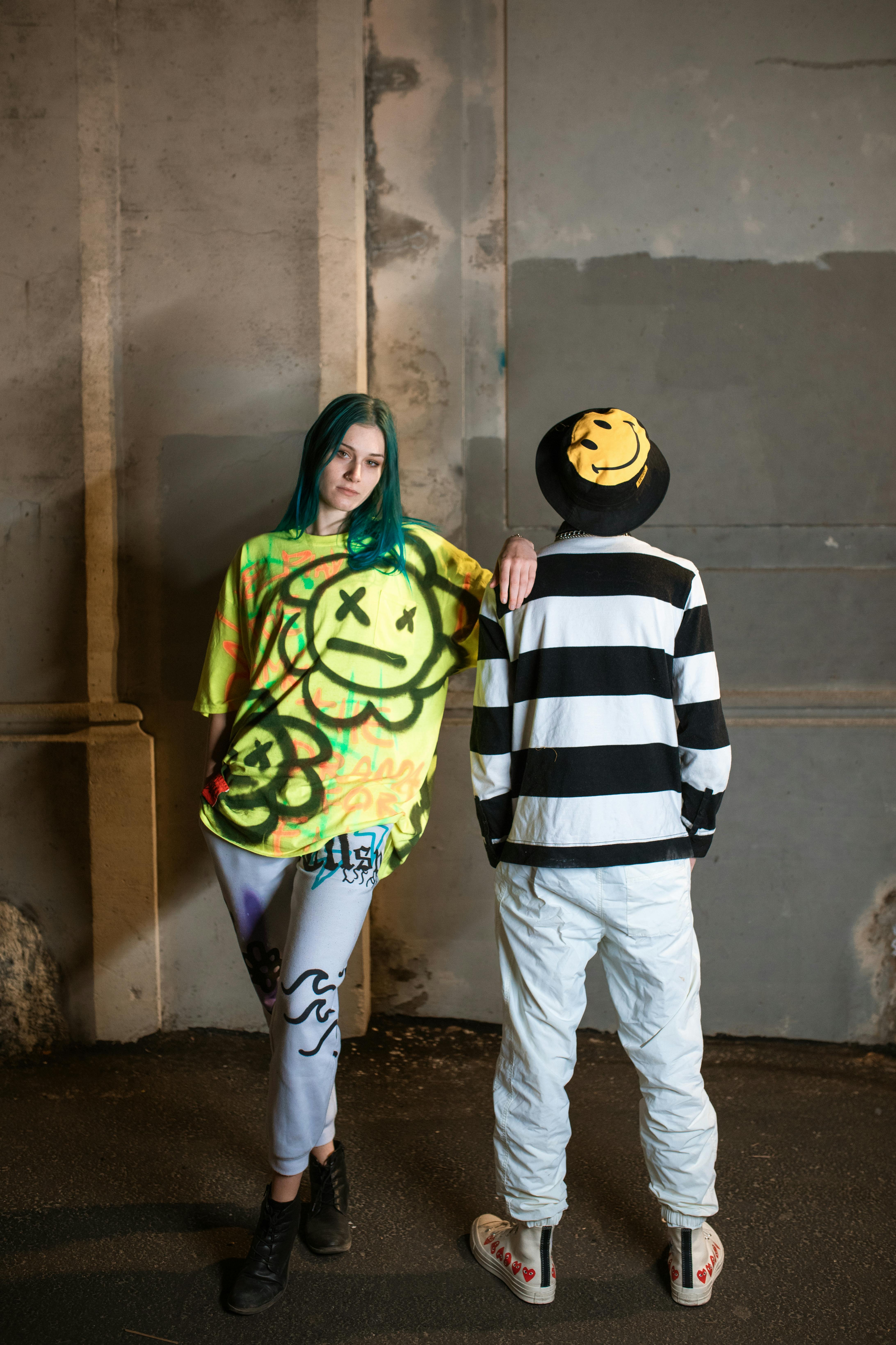 man in white pants standing beside woman in green and black jacket