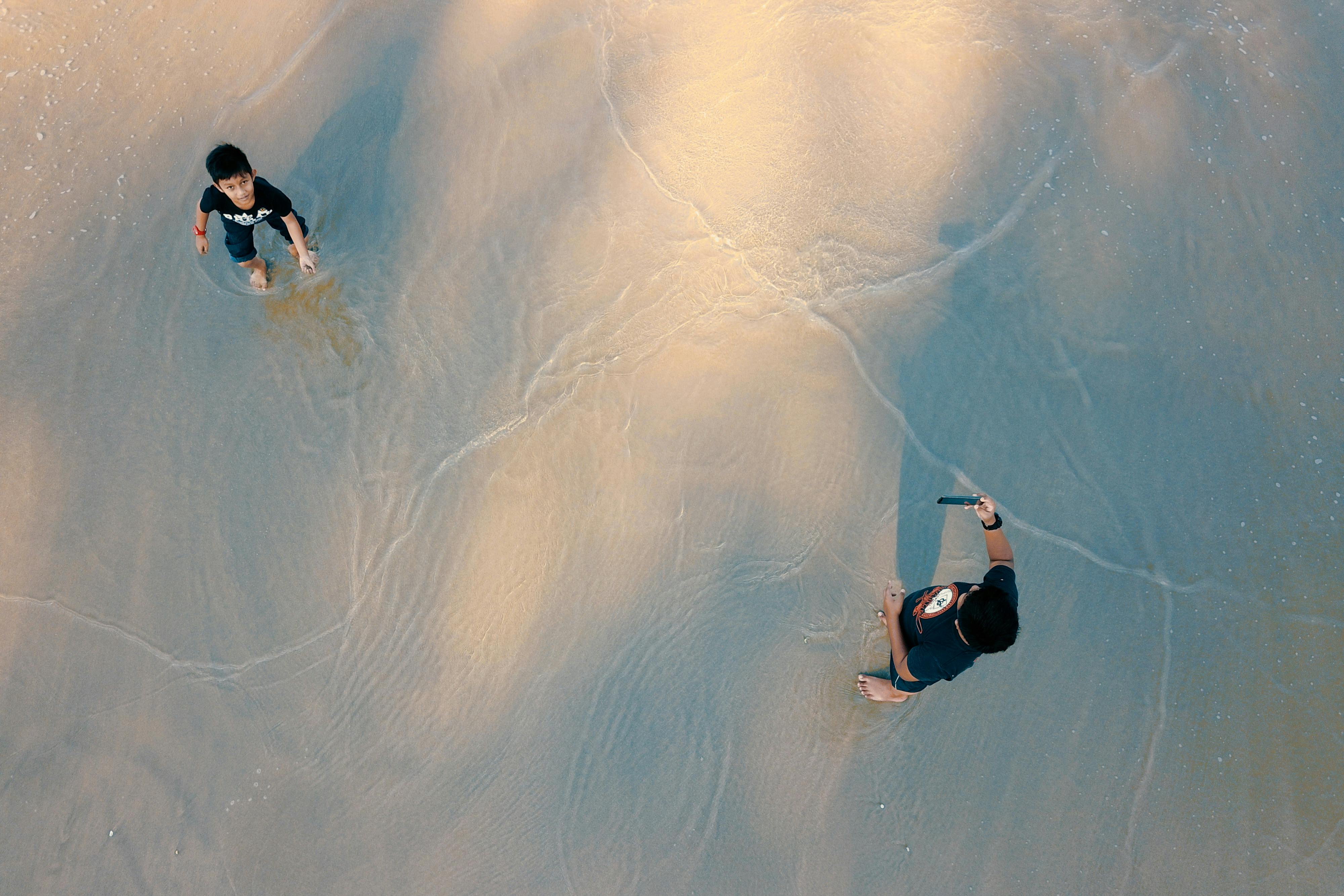 anonymous ethnic father with smartphone near son on wet beach