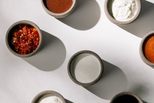 Free Top view of bowls with various sauces and dips casting shadows on a white surface. Stock Photo