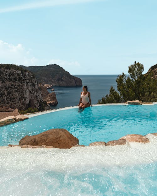 A Woman in White Swimsuit Sitting at the Pool Side