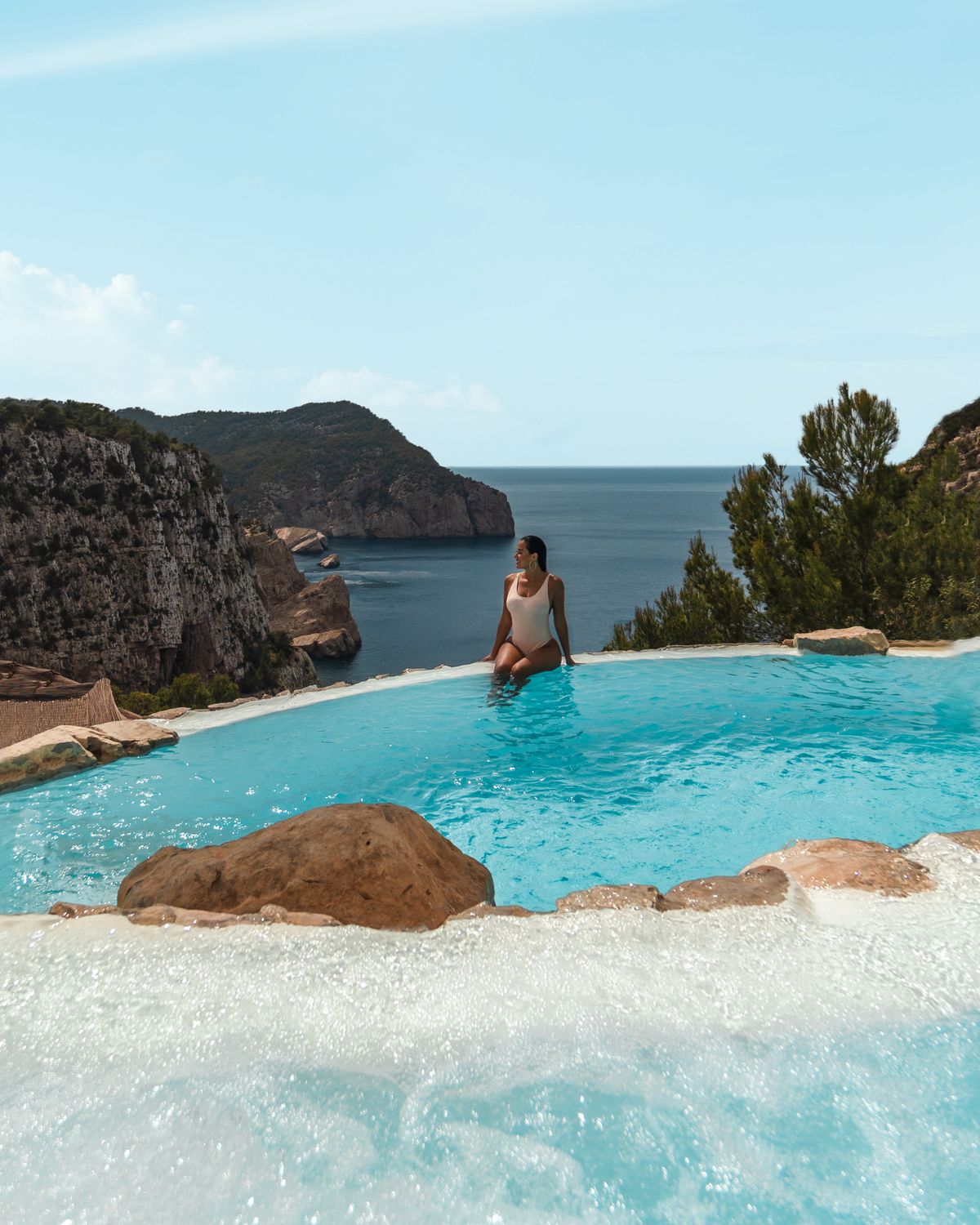 A woman in a white swimsuit poolside at a luxury Ibiza hotel