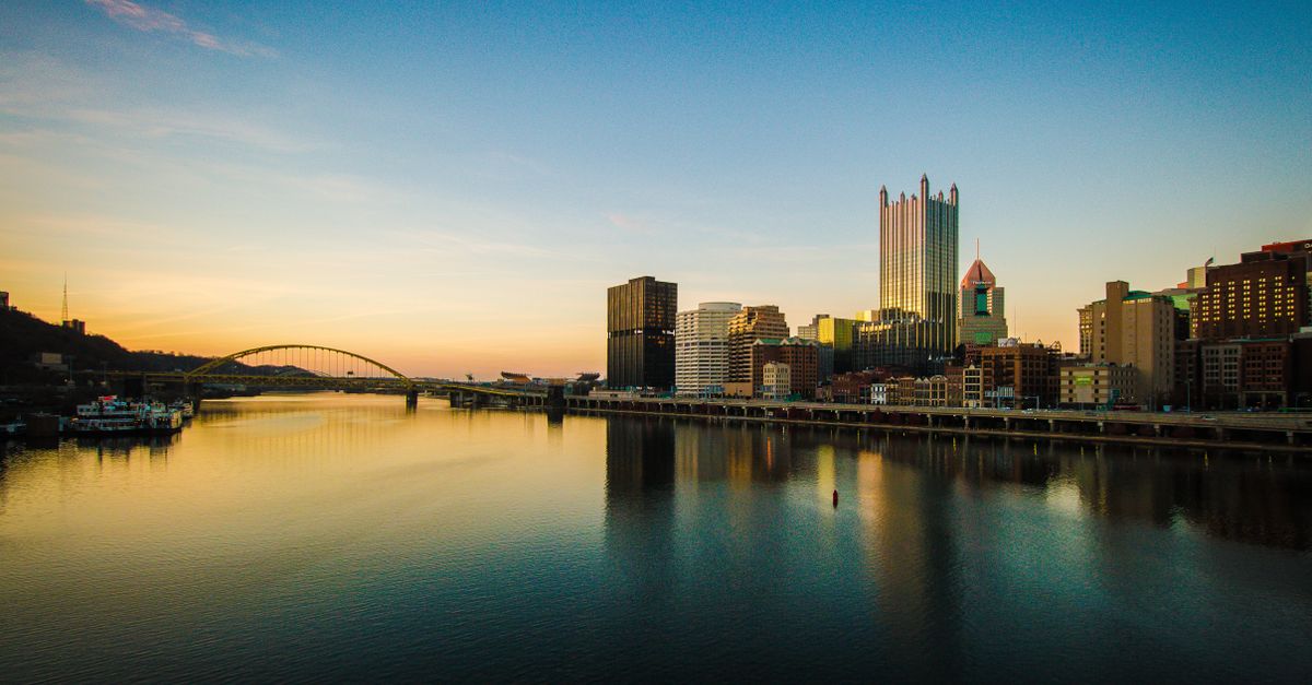 Beautiful sunset over the city skyline with reflections in the river, showcasing modern architecture and tranquil scenery.
