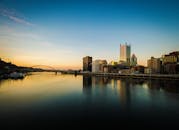 美丽的日落划过城市天际线，河流倒映着现代建筑与宁静的风景