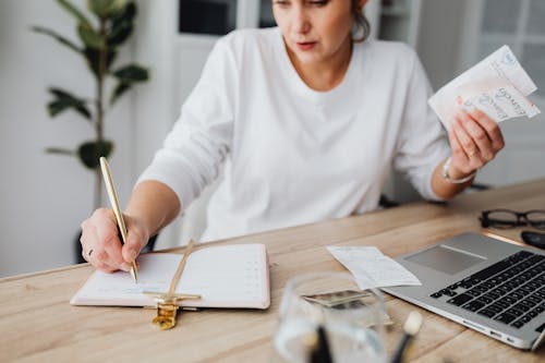 Woman Writing in a Notepad at the Desk 