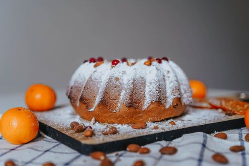 Free Close-up of a powdered Bundt cake with oranges and almonds on a tray. Stock Photo