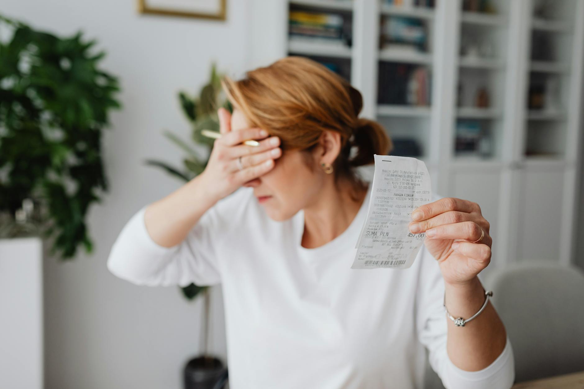 Woman experiencing stress while reviewing household expenses at home.