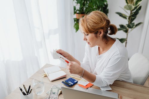 Woman at Wooden Desk Reading a Receipt