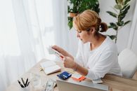 在办公室，一位坐在桌前的妇女正用计算器和纸质收据处理财务事务