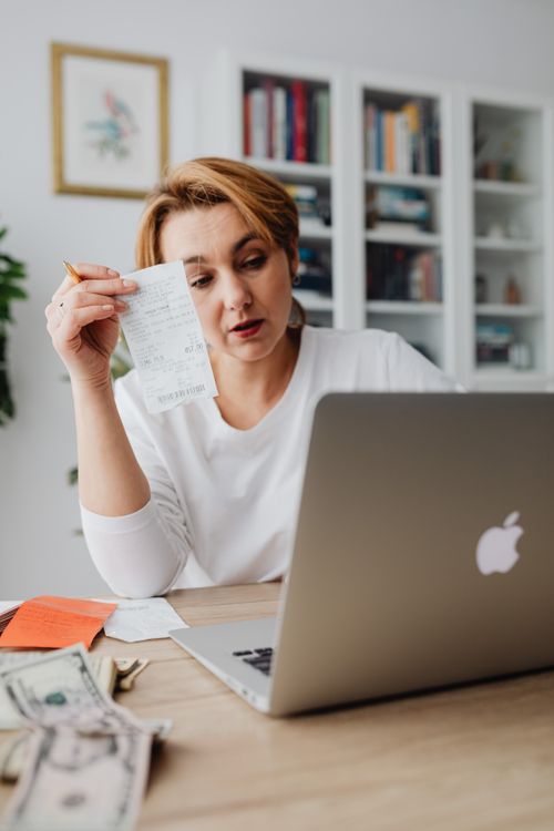 Woman Making Calculations by Counting Money and Receipts on a Laptop ...