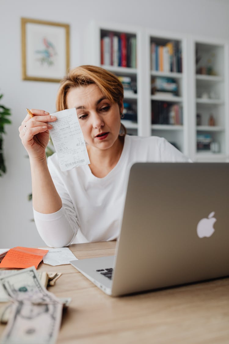 Woman Making Calculations By Counting Money And Receipts On A Laptop 