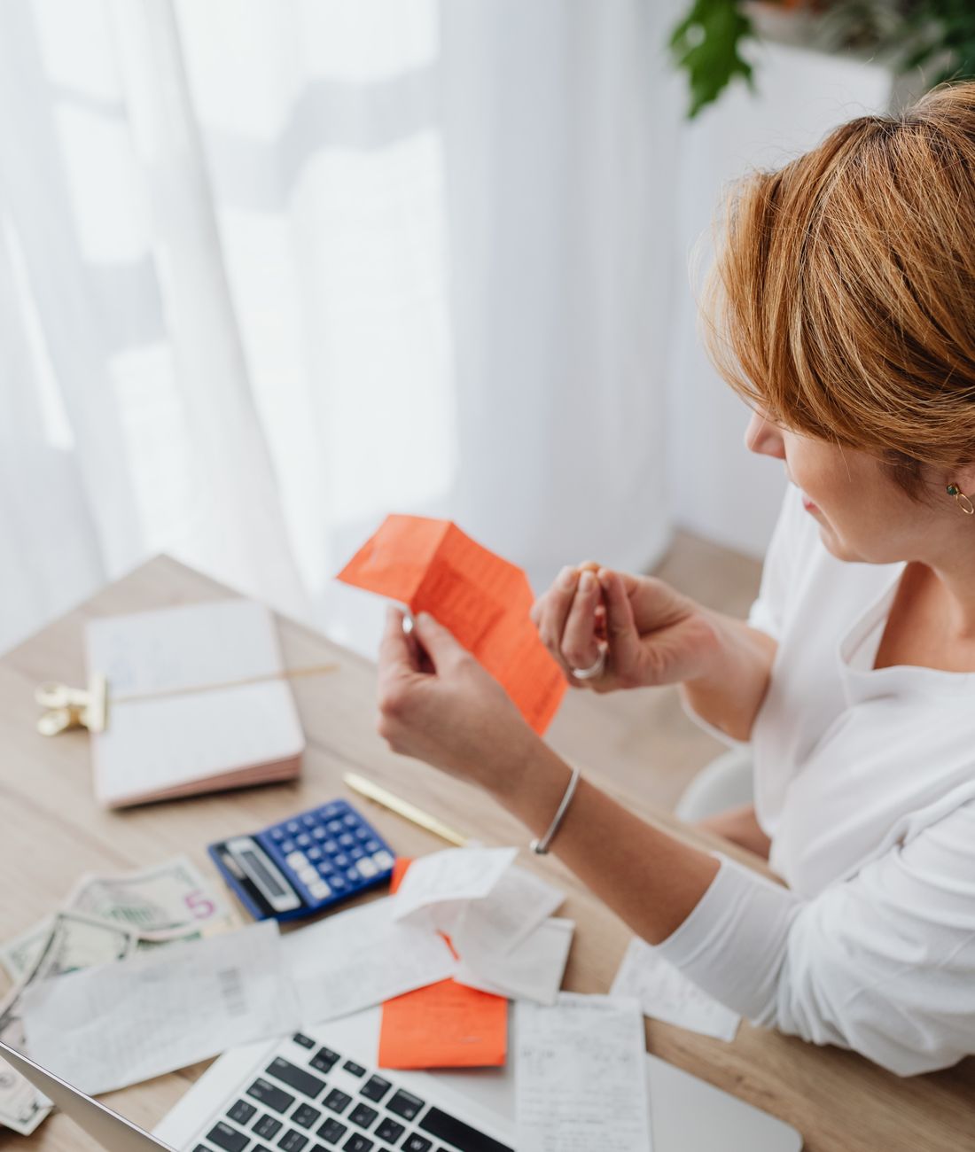 A person paying a monthly bill with a calculator and bank statement