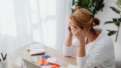 Woman stressed over financial receipts at a desk, dealing with expenses and calculations.