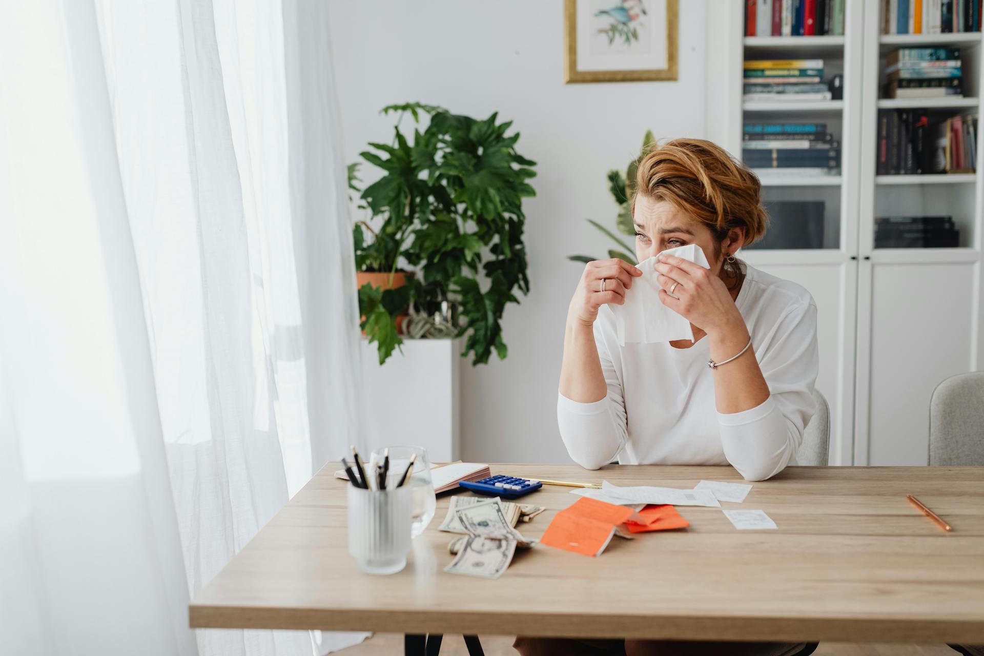 Woman in an Office with Banknotes on Table, Crying