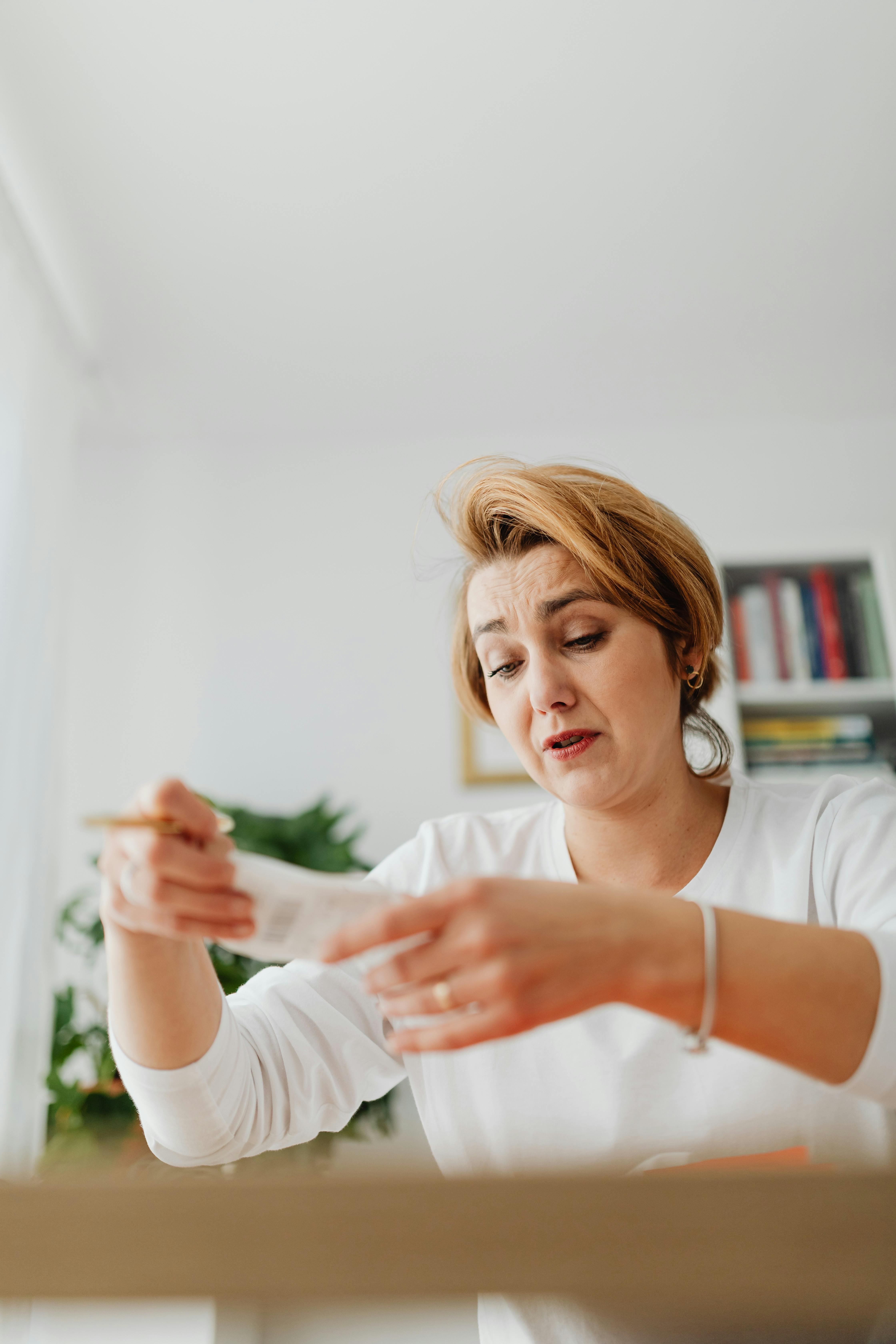 worried woman sitting behind the desk and holding a piece of paper