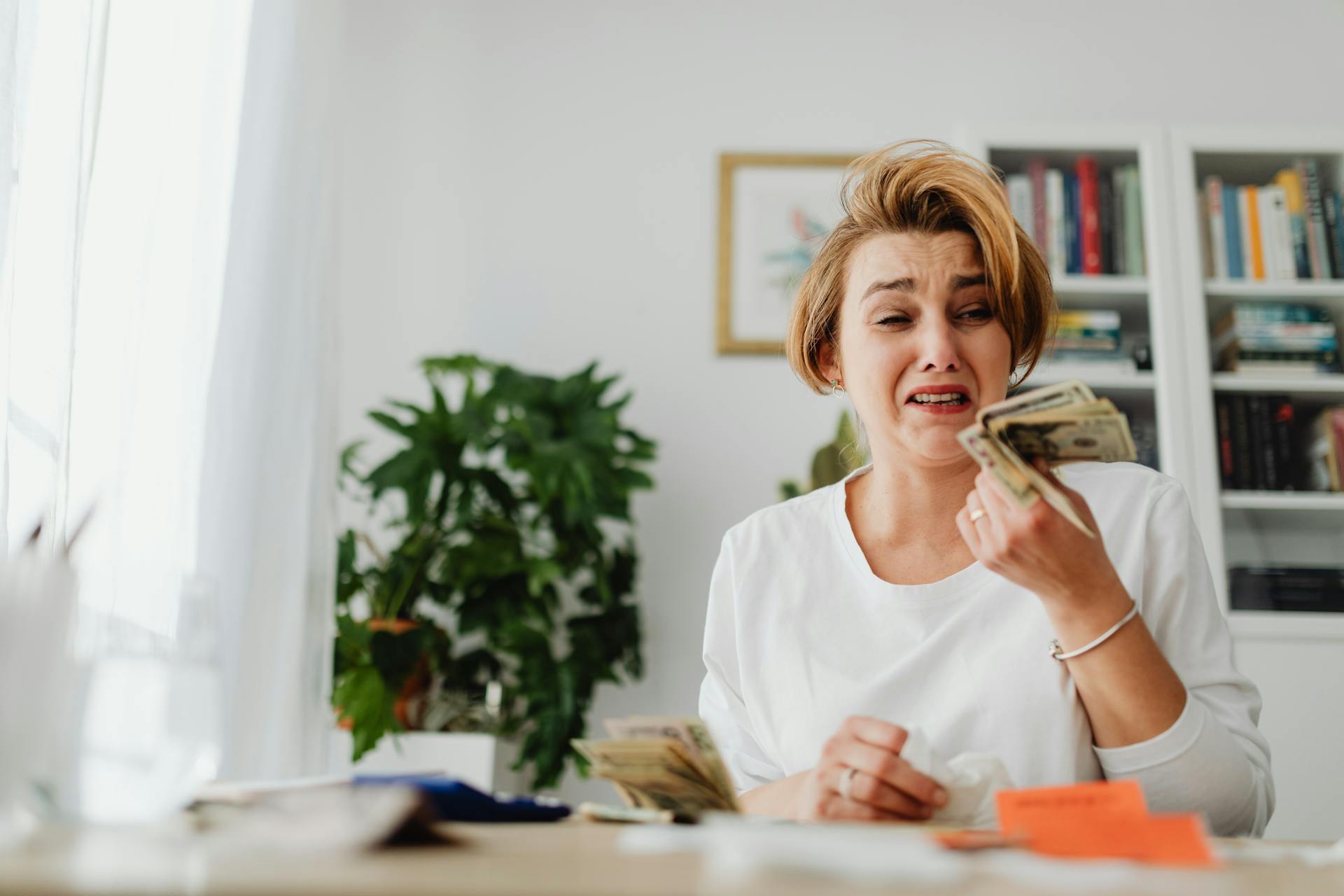 Woman Counting Money and Paying Bills with Sadness