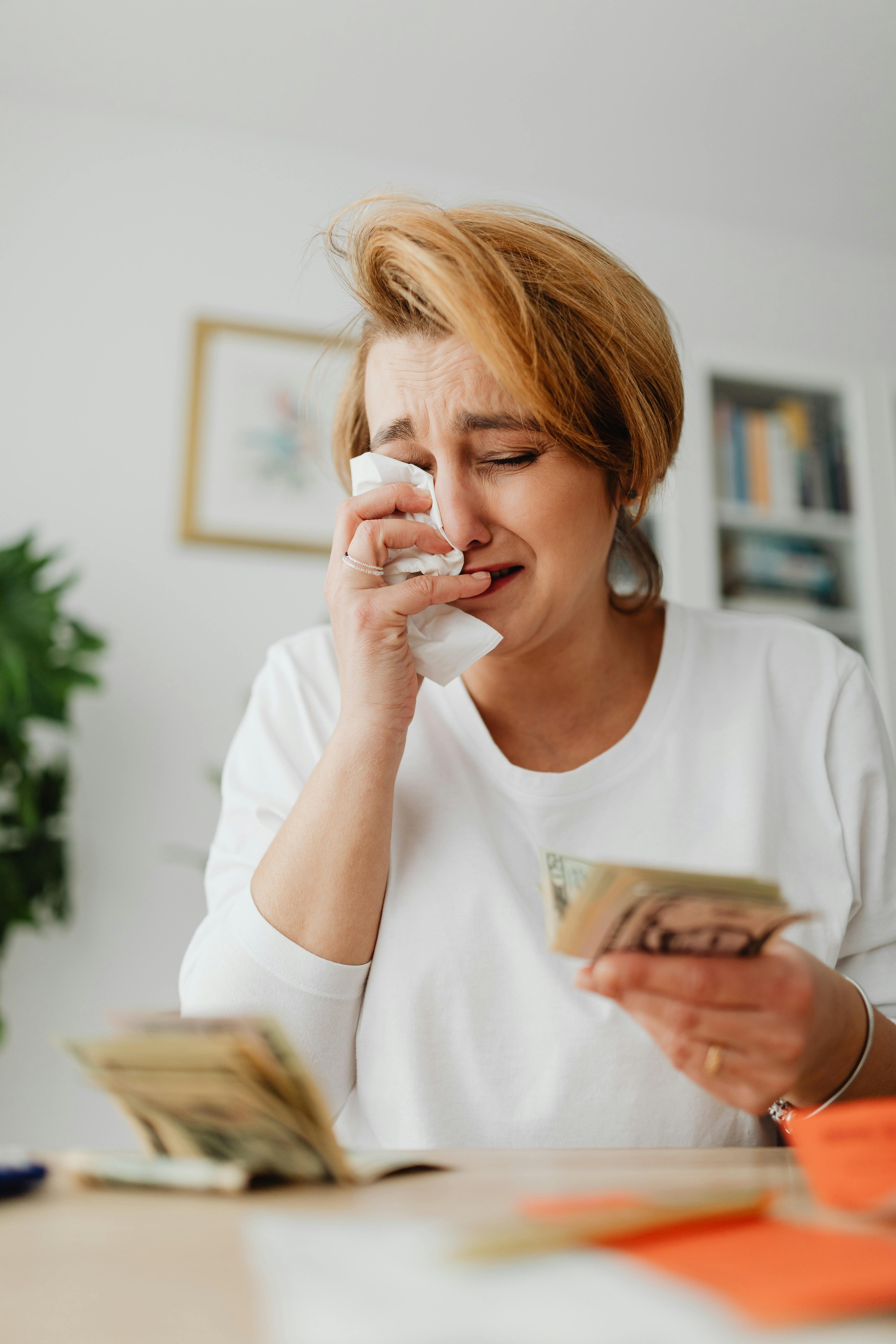 woman holding money in a hand and crying