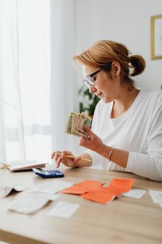 Woman counting cash and planning budget at indoor home office setting.