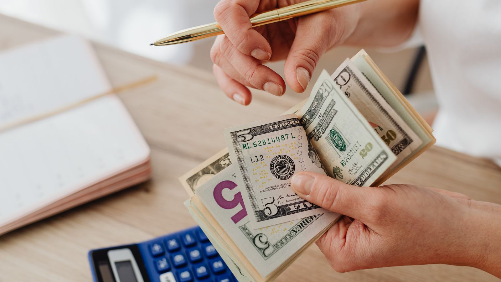 Persona organizando dinero, recibos y una calculadora