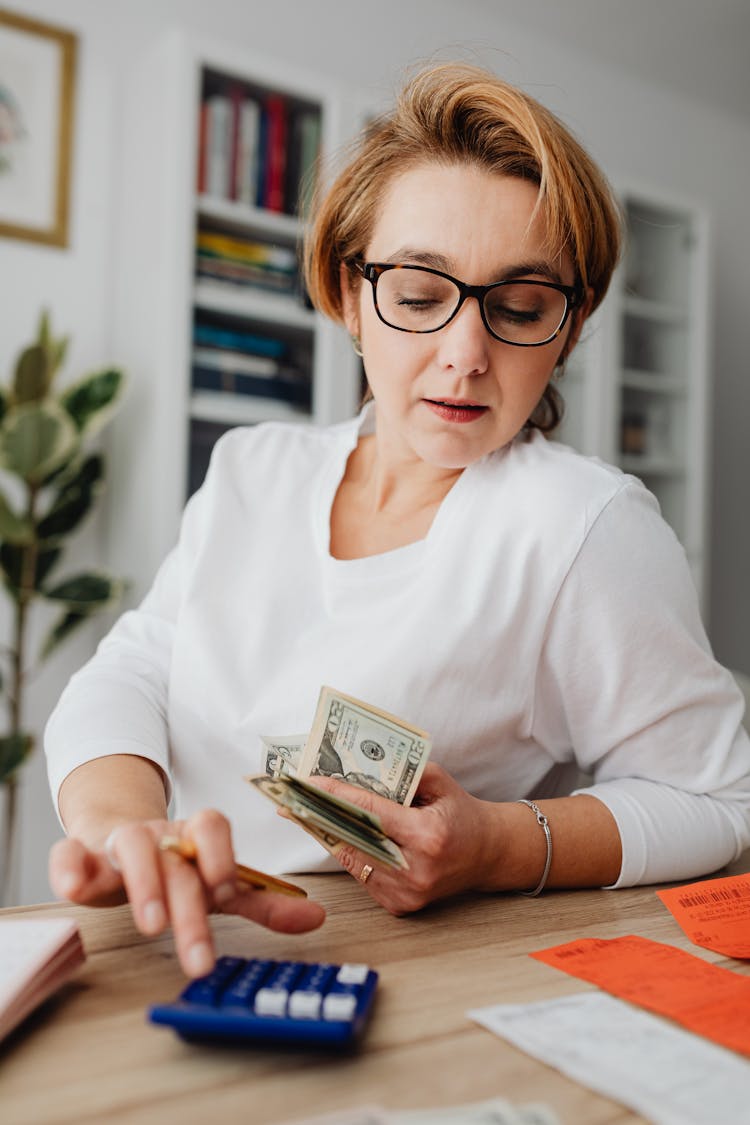 Woman Counting Money And Receipts On A Calculator 