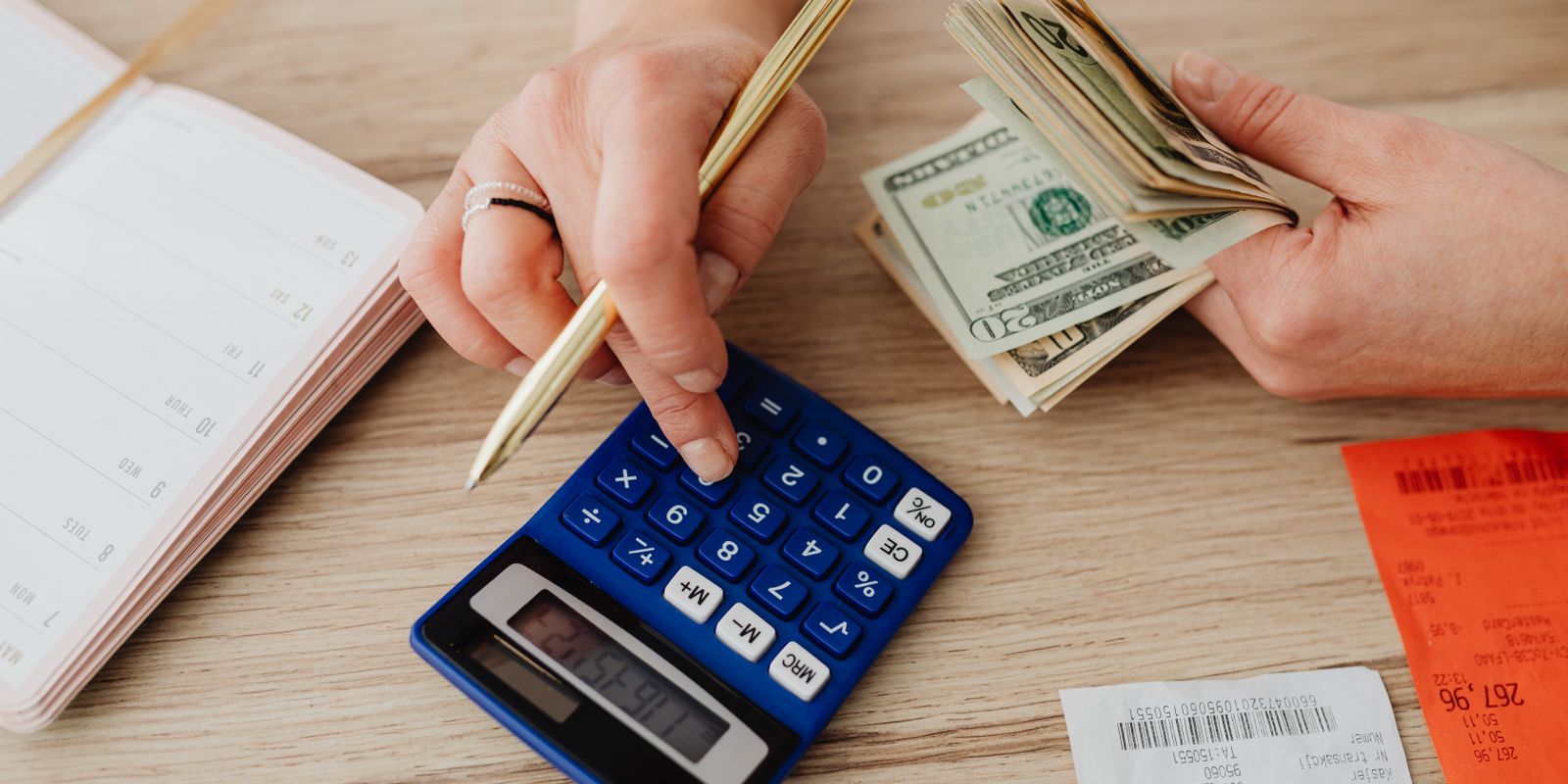 Hands handling cash and calculator for budget planning. Modern financial scene.