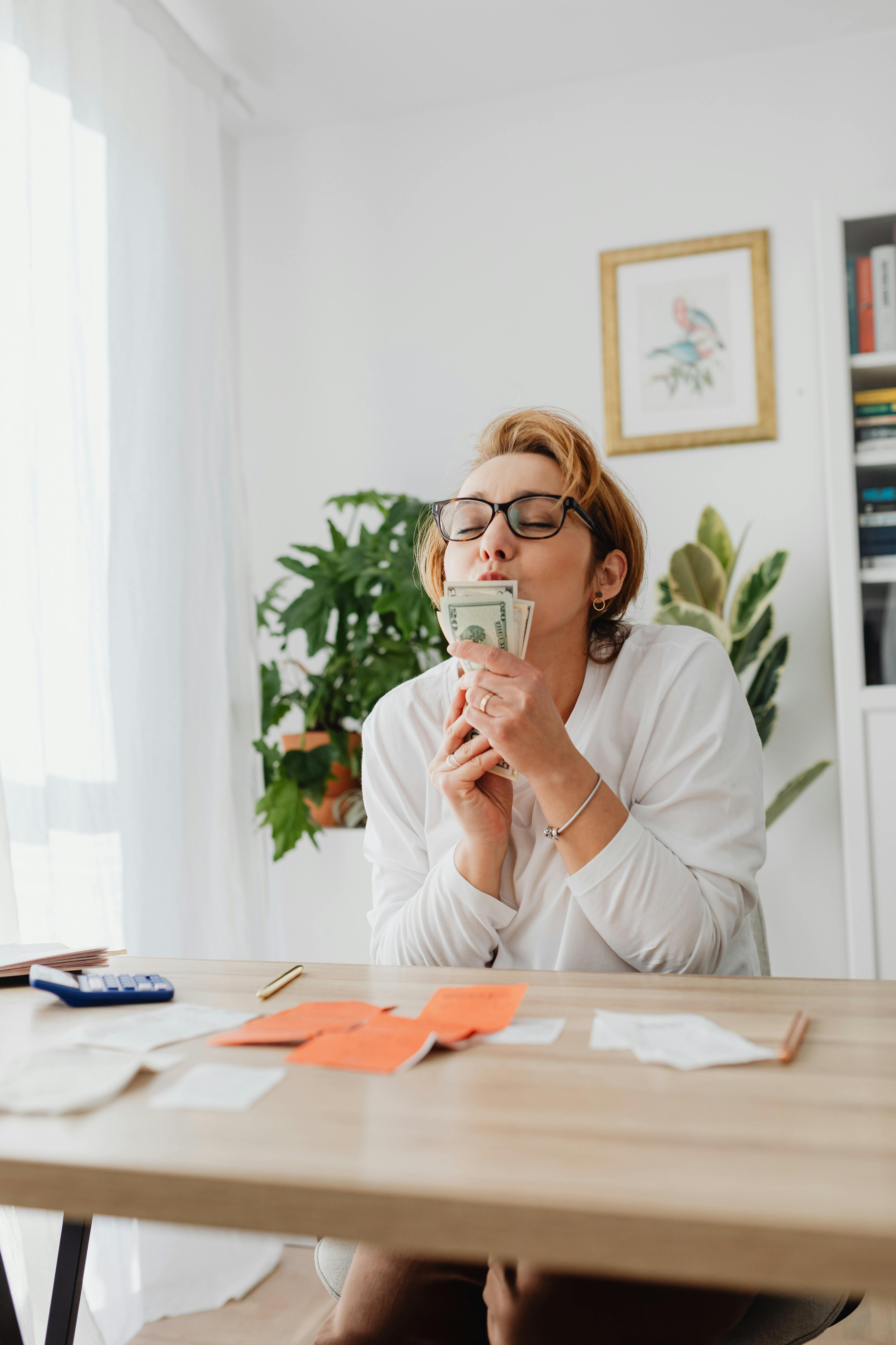 woman in white long sleeve shirt kissing banknotes