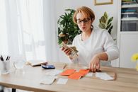 一名女子坐在桌子旁数现金，并用附近的计算器整理收据