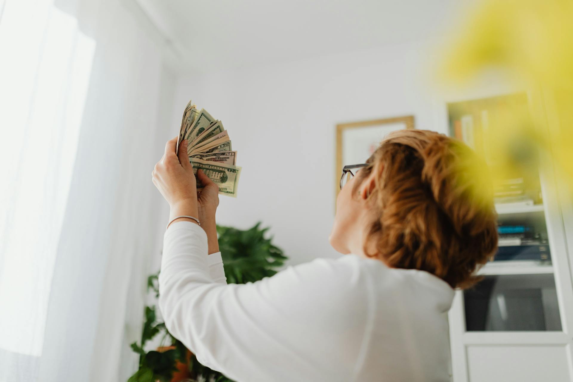 Person in White Long Sleeve Shirt Holding Dollar Bills