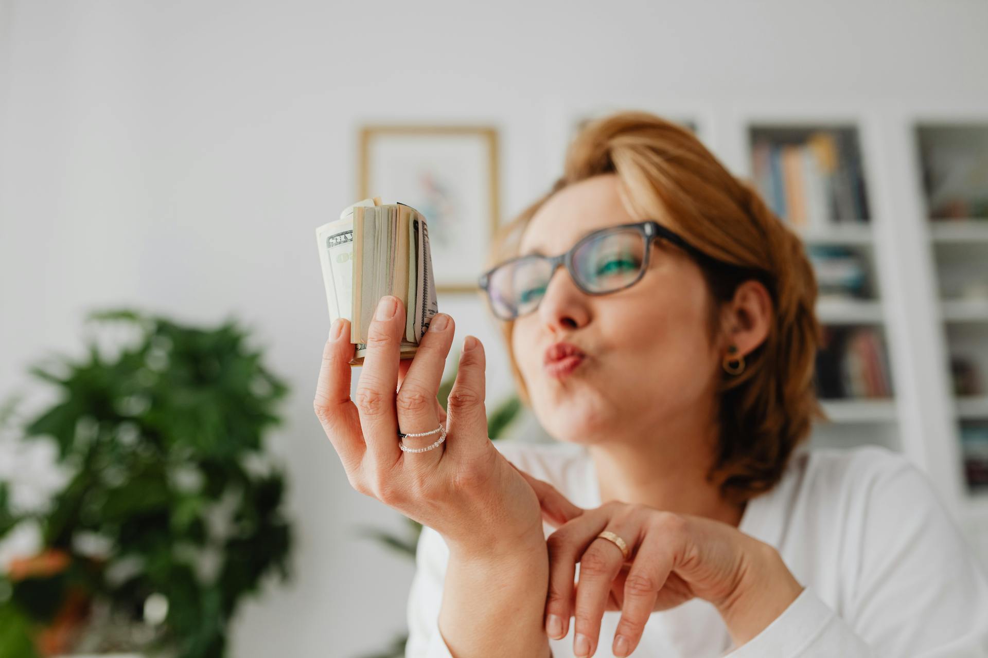 Woman Blowing Kiss Towards Wad of Banknotes in her Hand