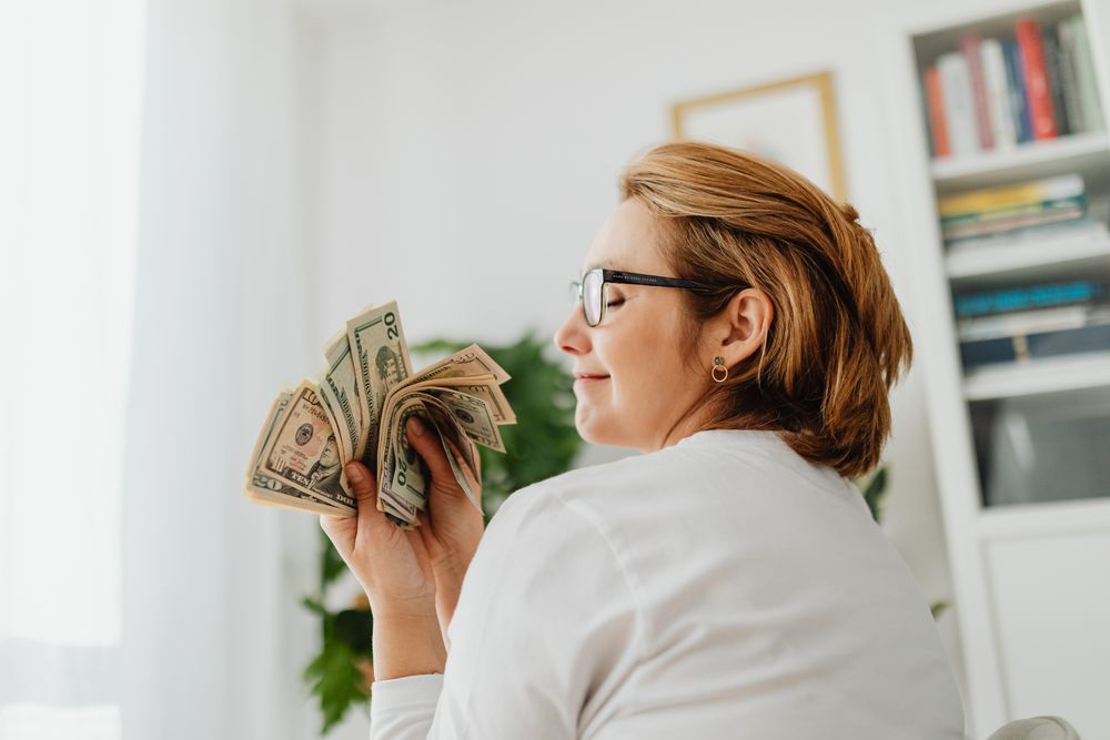 Confident woman in glasses holding US dollar bills