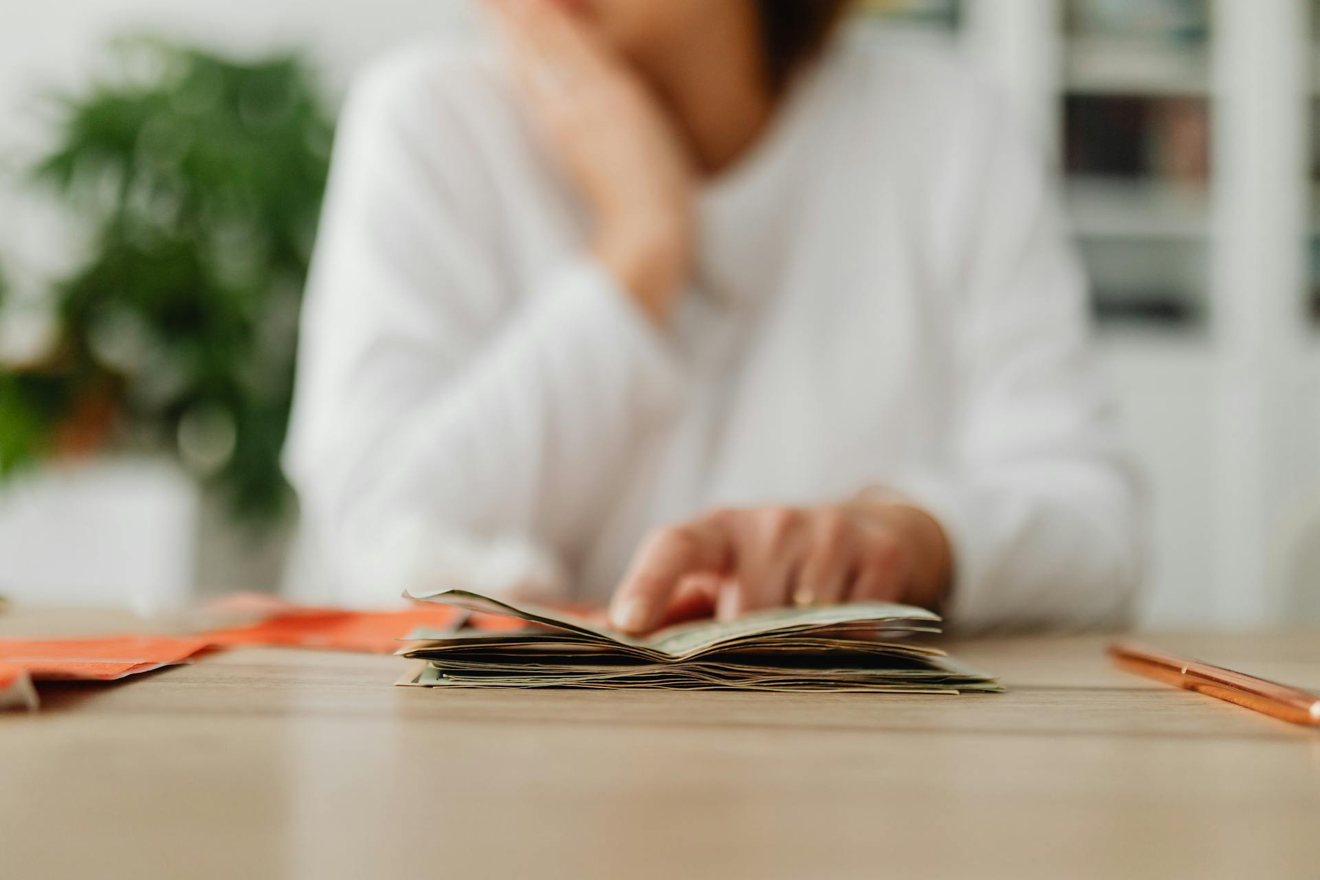 Woman Sitting Behind the Desk and Looking at Money and Receipts