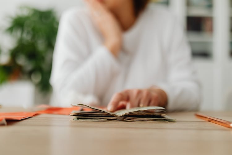 Woman Sitting Behind The Desk And Looking at Money And Receipts 