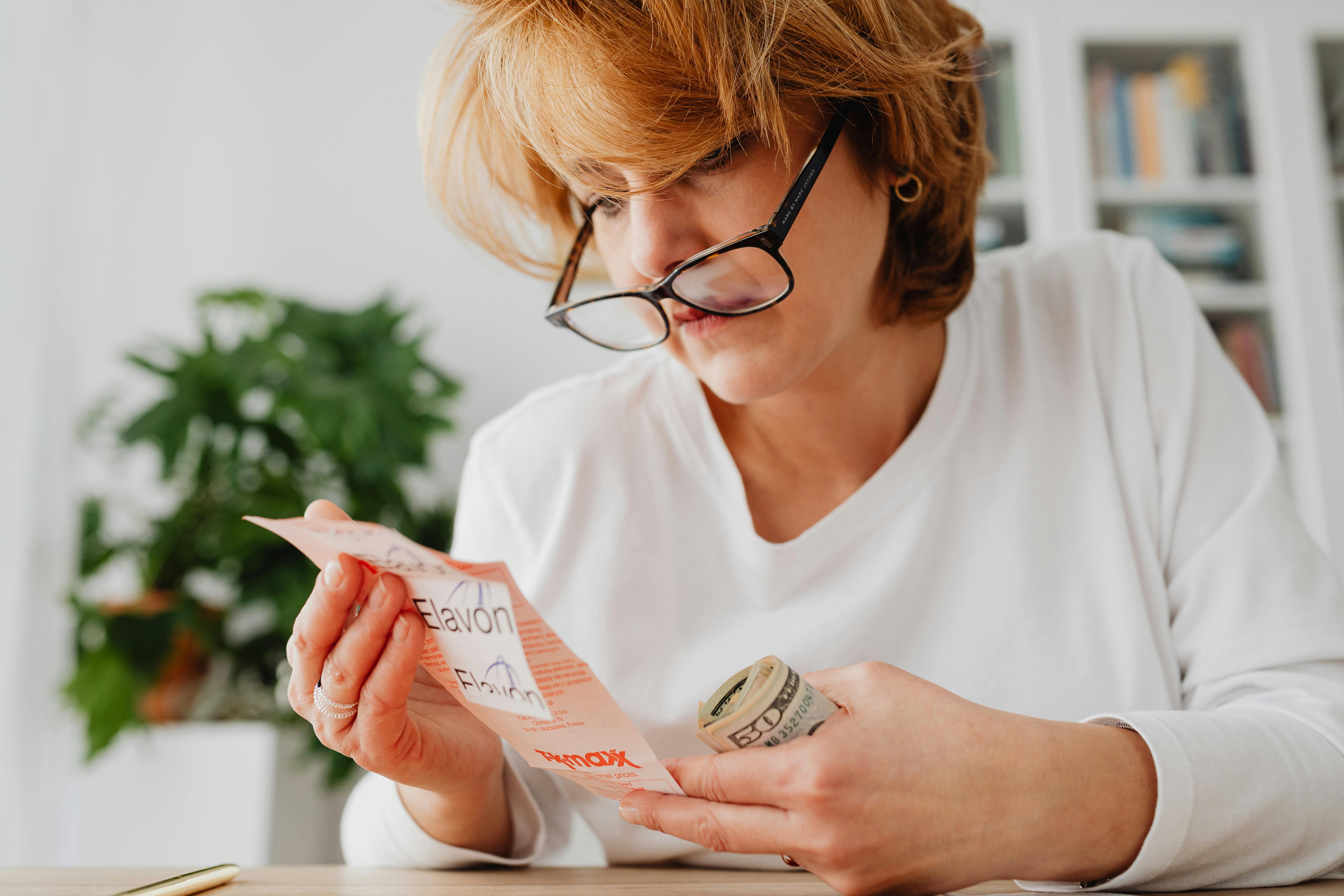 woman in white long sleeves staring at the paper bill