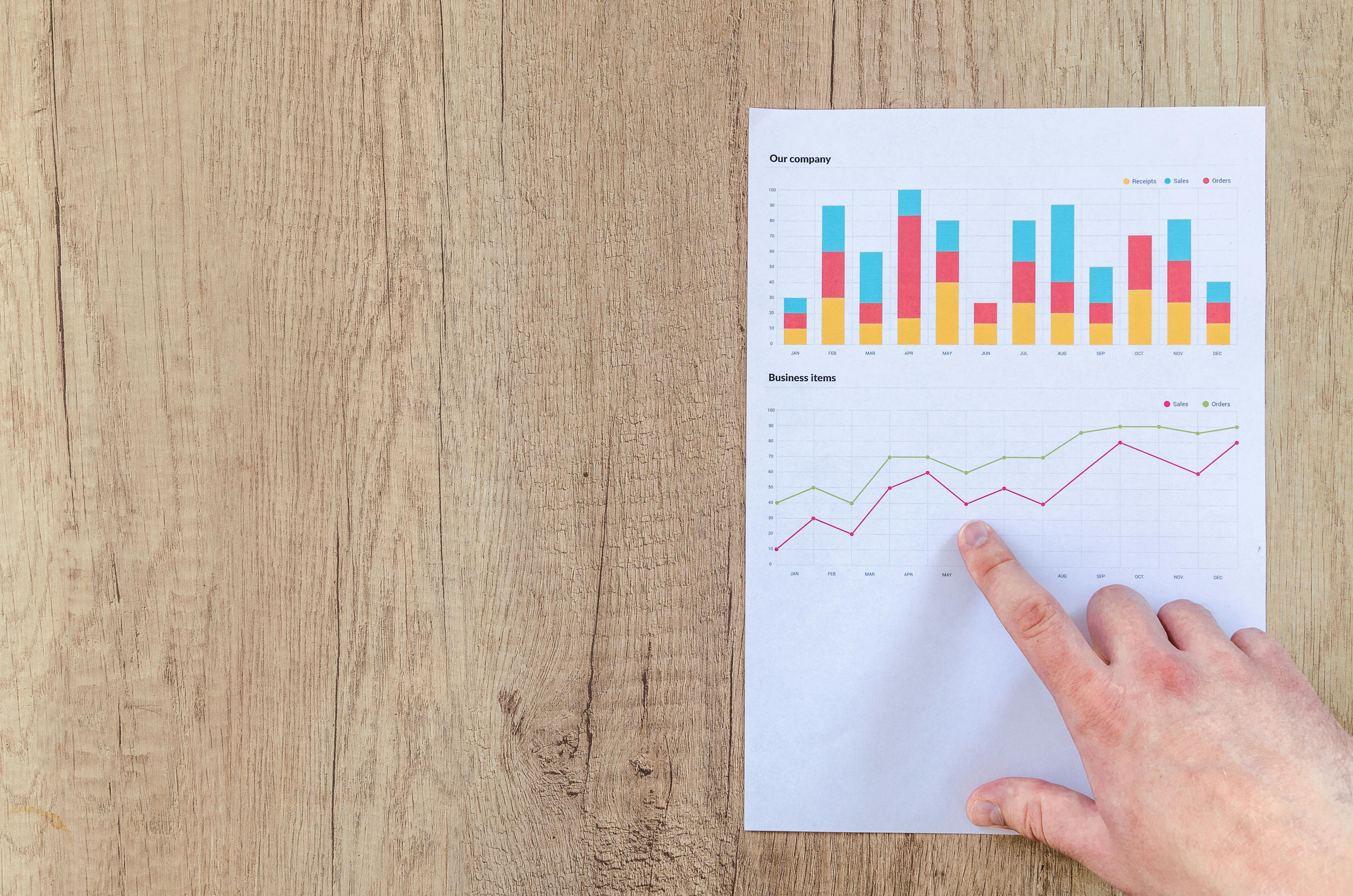 person pointing paper line graph