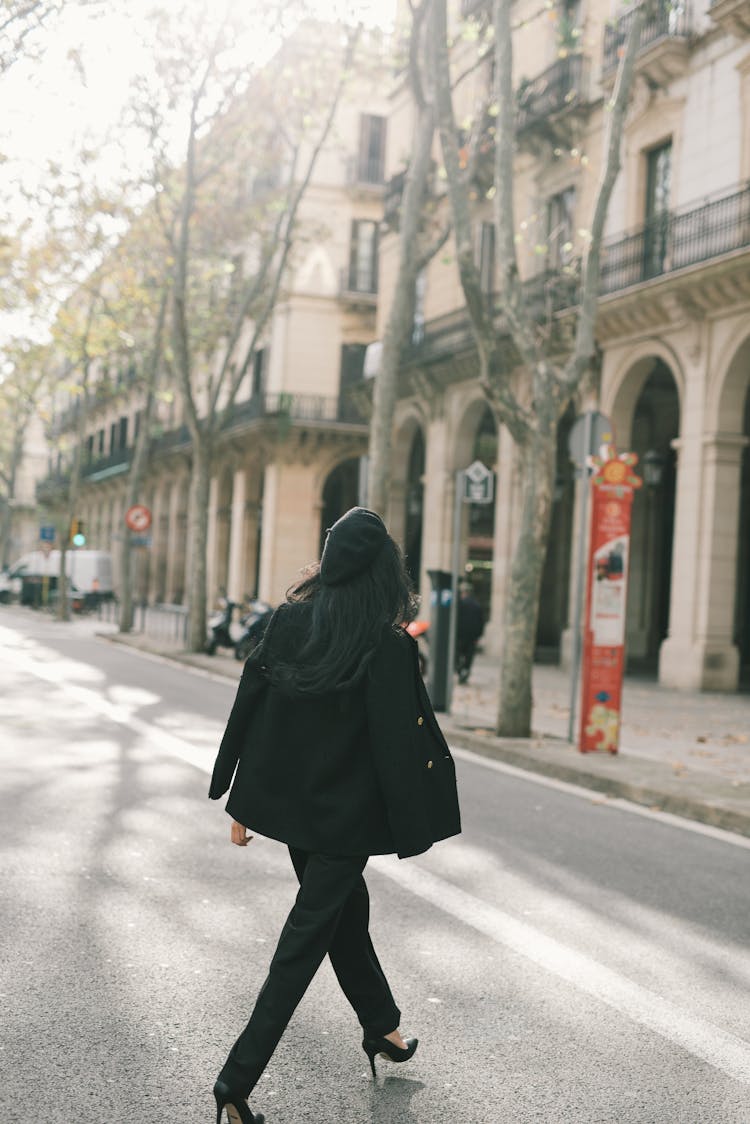 A Woman In Black Clothes Walking On The Road