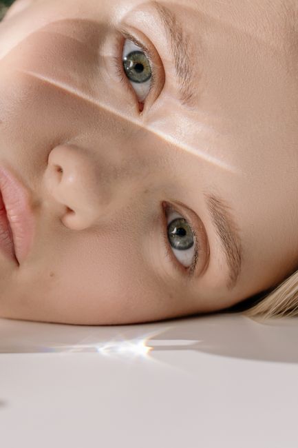 Detailed close-up of a woman's face with striking green eyes reflecting light.