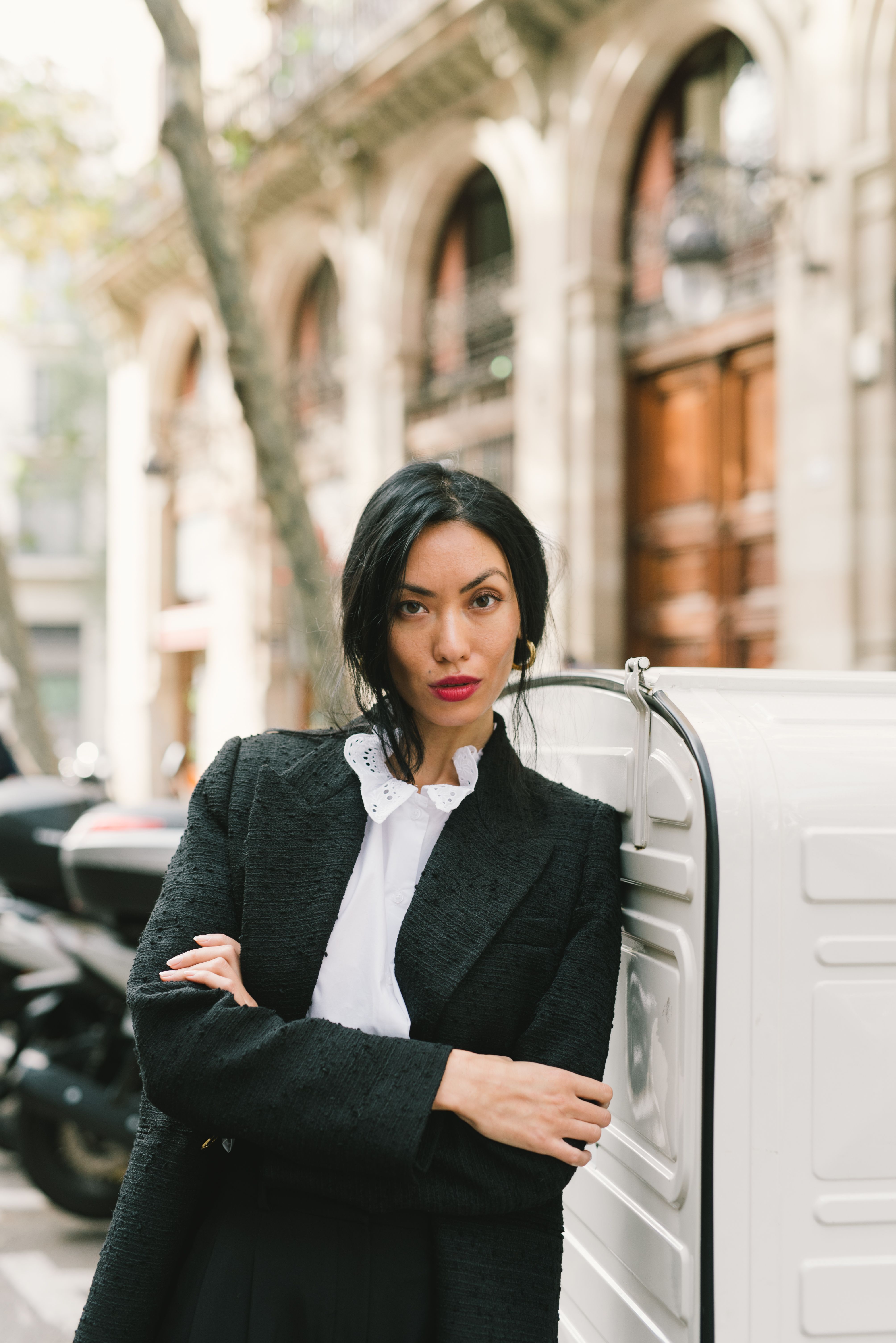 一位自信的女性身穿黑色西装外套，在户外摆姿势展示街头时尚