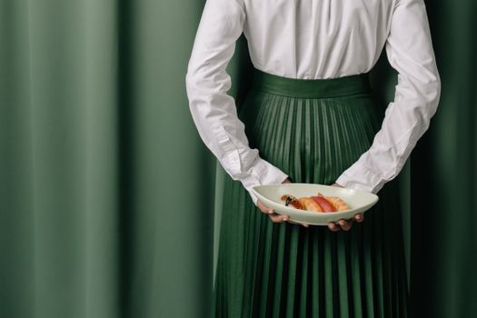 Person in White Long Sleeve Shirt and Green Skirt Holding Orange Fruit