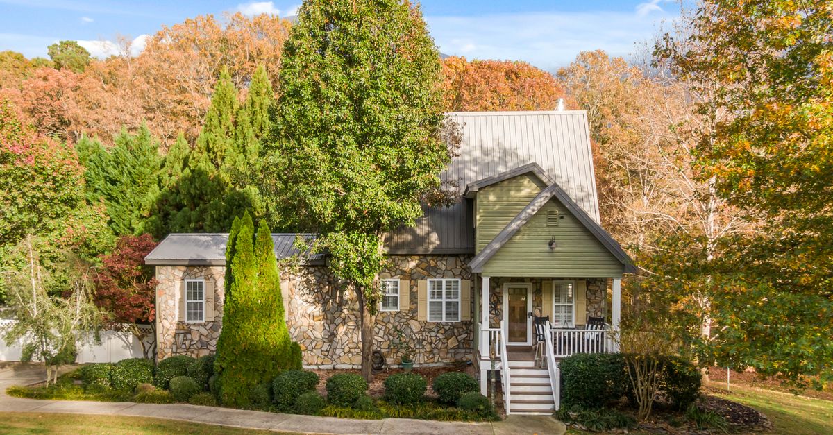 A picturesque stone cottage set amidst vibrant fall foliage, offering a serene and inviting atmosphere.