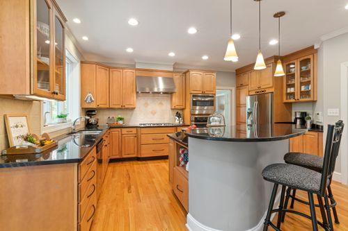 Free Spacious modern kitchen featuring wooden cabinets, island, and stainless steel appliances. Stock Photo