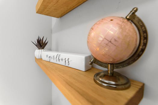 Close-up of a stylish shelf featuring a pink globe and #girlboss decor for modern workspace inspiration.