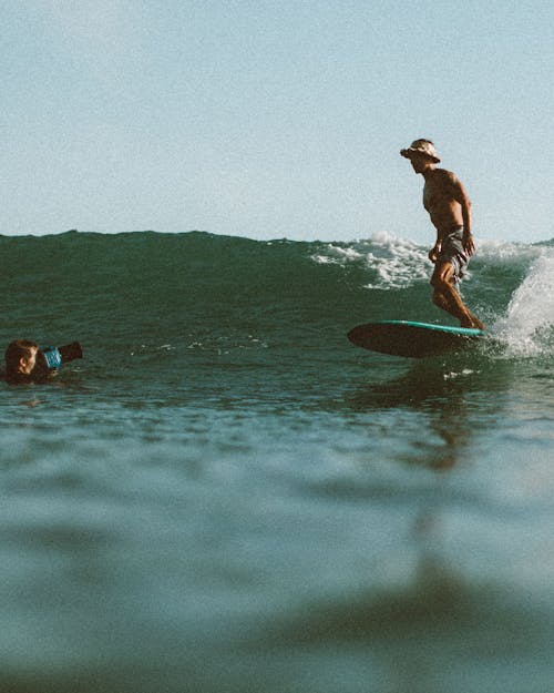 Unrecognizable man taking pictures of surfer in water