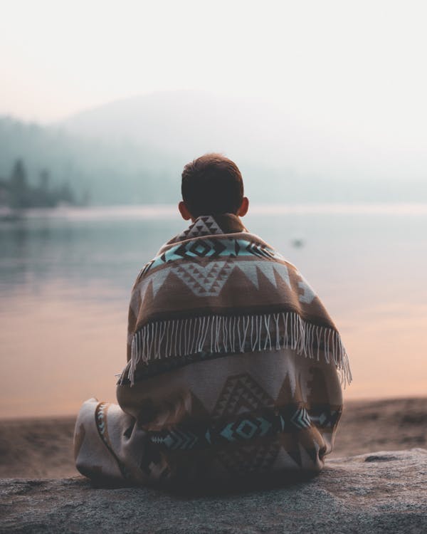 Free Man Sitting on Sand Facing Body of Water Stock Photo