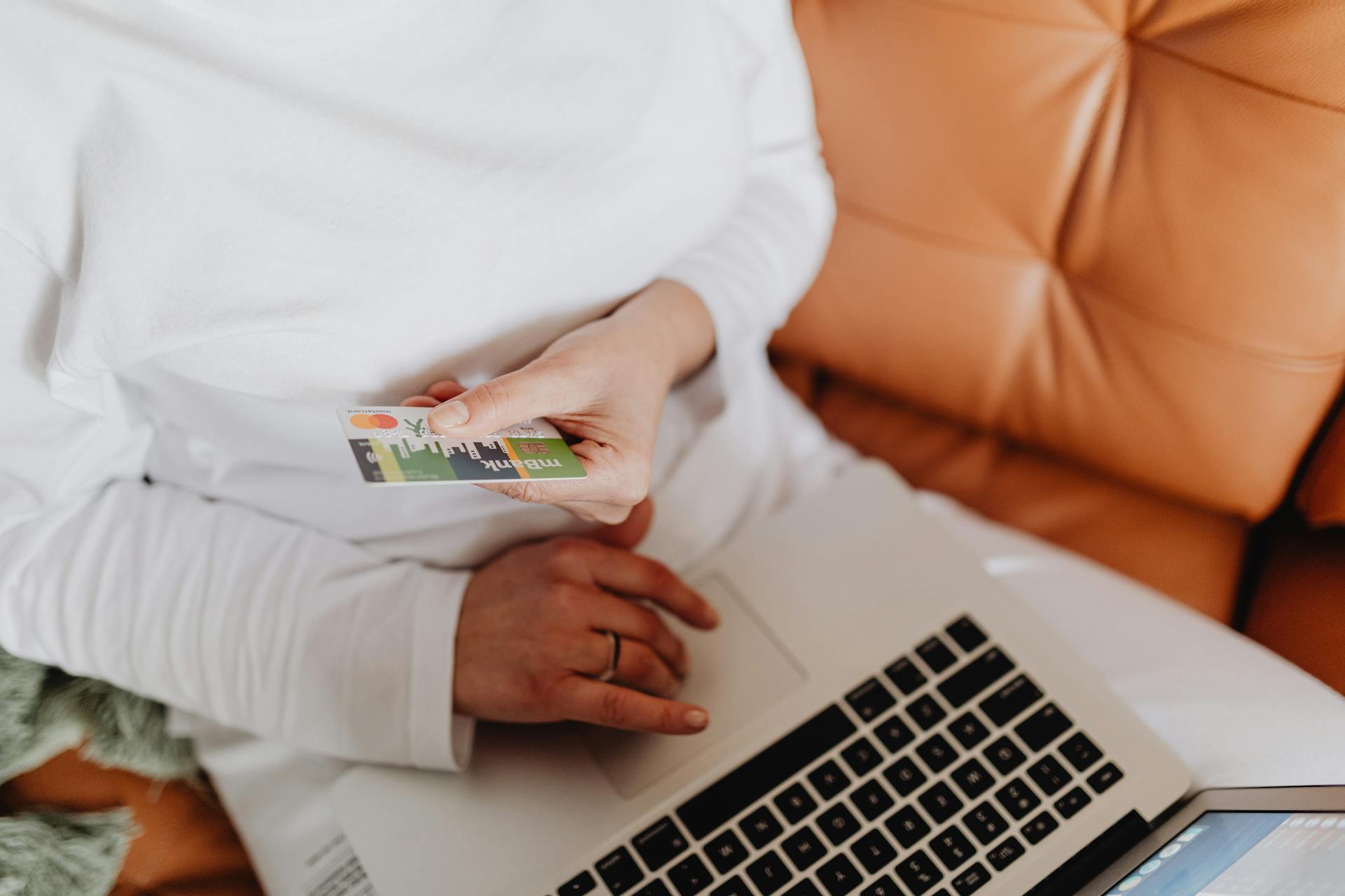 Woman Holding a Debit Card and Using a Laptop