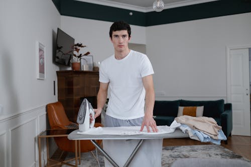Man in White Crew Neck Shirt Ironing Clothes