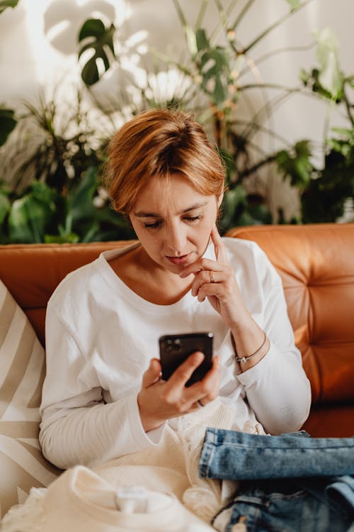 Free Woman Sitting on Couch Browsing Cellphone Stock Photo