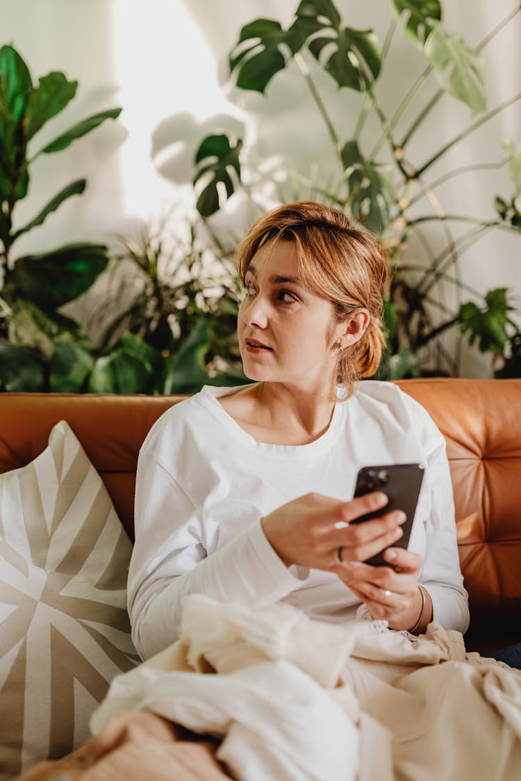 Woman Texting While Sitting Under Covers On Sofa