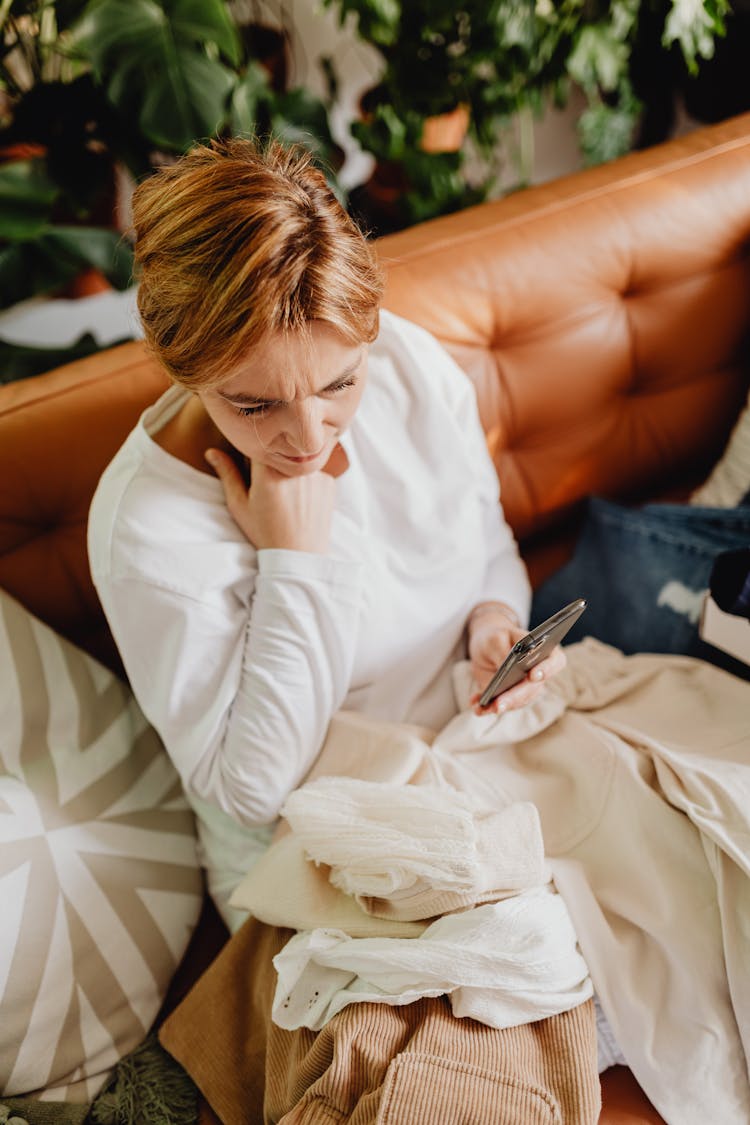 Woman Sitting On The Sofa And Using Her Phone