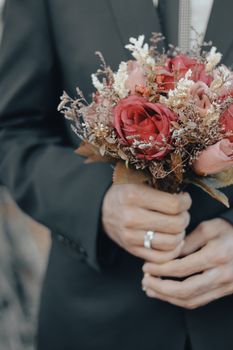 Elegant close-up of a groom holding a bouquet during a wedding.