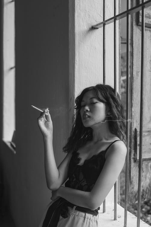 Grayscale Photo of a Woman Smoking a Cigarette