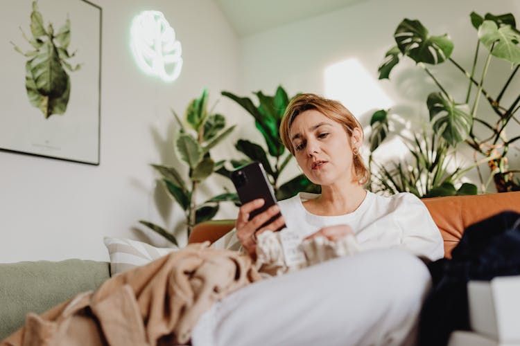 Woman Sitting On A Couch And Using A Phone 